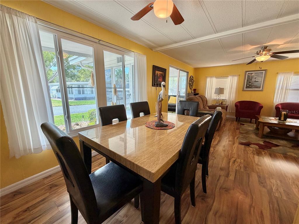 A dining area with a stone-topped table and black chairs opens into a living room — 126 CHESTNUT STREET, LEESBURG, FL