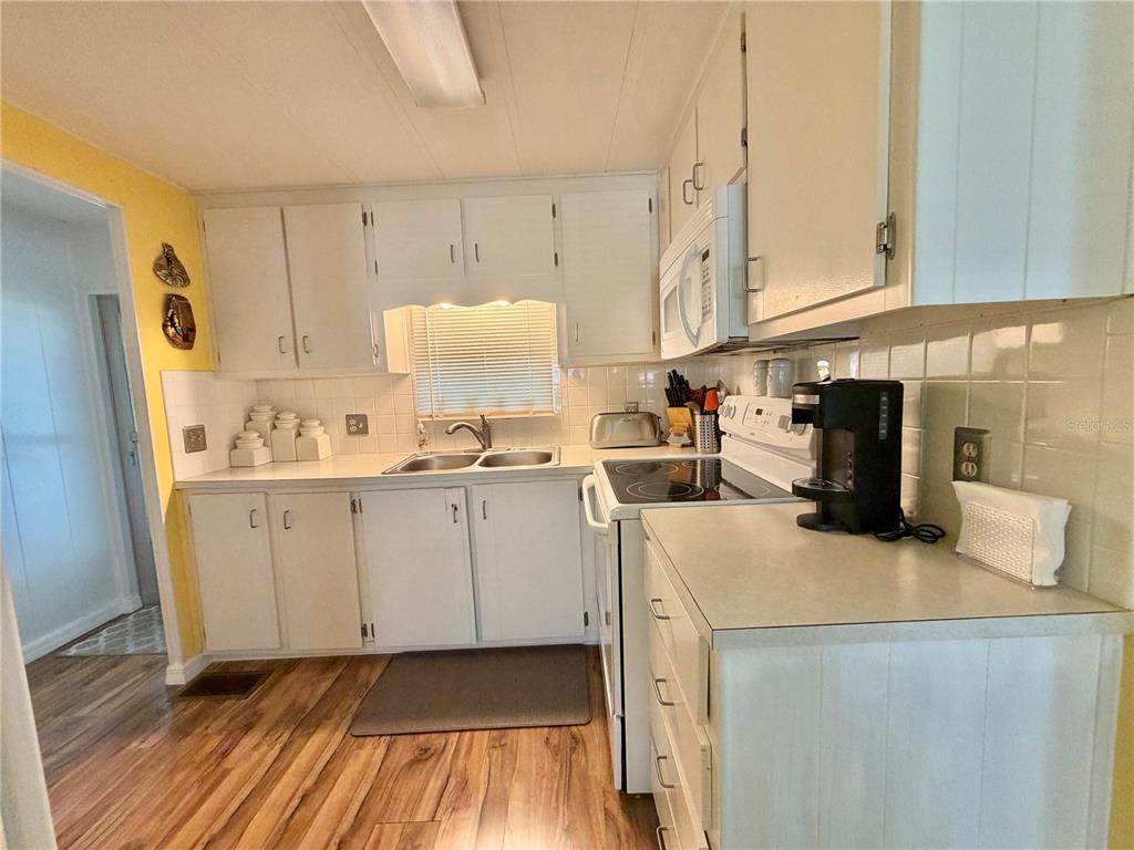 A kitchen with white cabinets, a double sink, a stove, and wood-look flooring — 126 CHESTNUT STREET, LEESBURG, FL