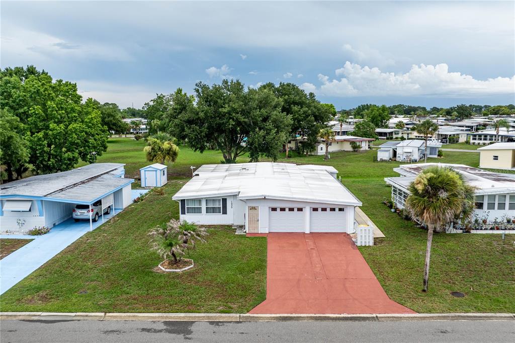An aerial view of a single-story house with a white exterior and a red driveway — 1030 CAPELLA DRIVE, TAVARES, FL