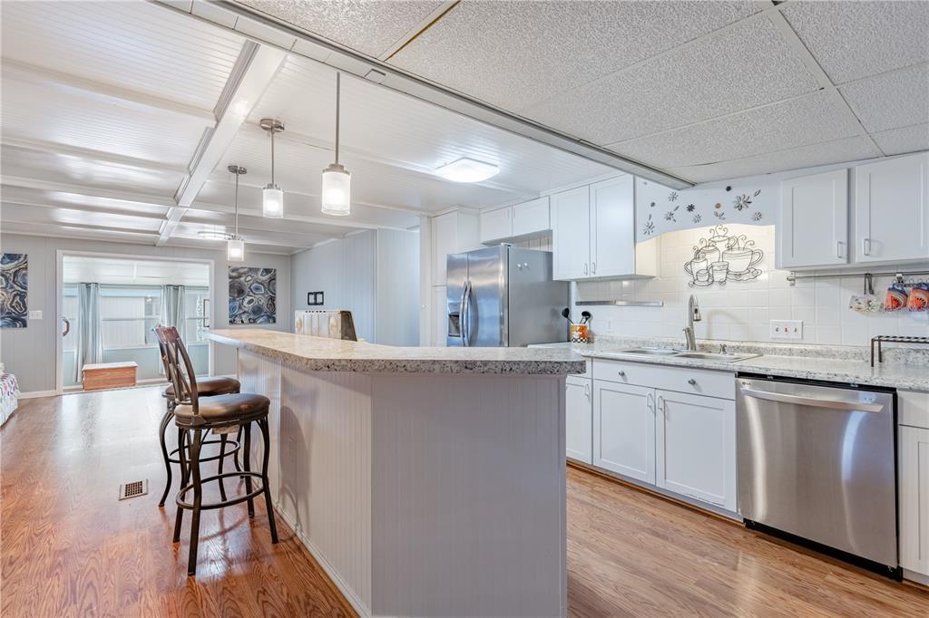A kitchen with white cabinets, stainless steel appliances, and a breakfast bar with two stools — 1030 CAPELLA DRIVE, TAVARES, FL