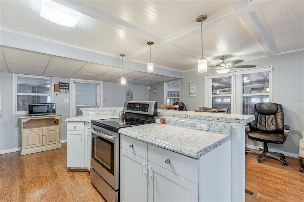 A kitchen features white cabinets, granite countertops, stainless steel appliances, and wood-look flooring — 1030 CAPELLA DRIVE, TAVARES, FL