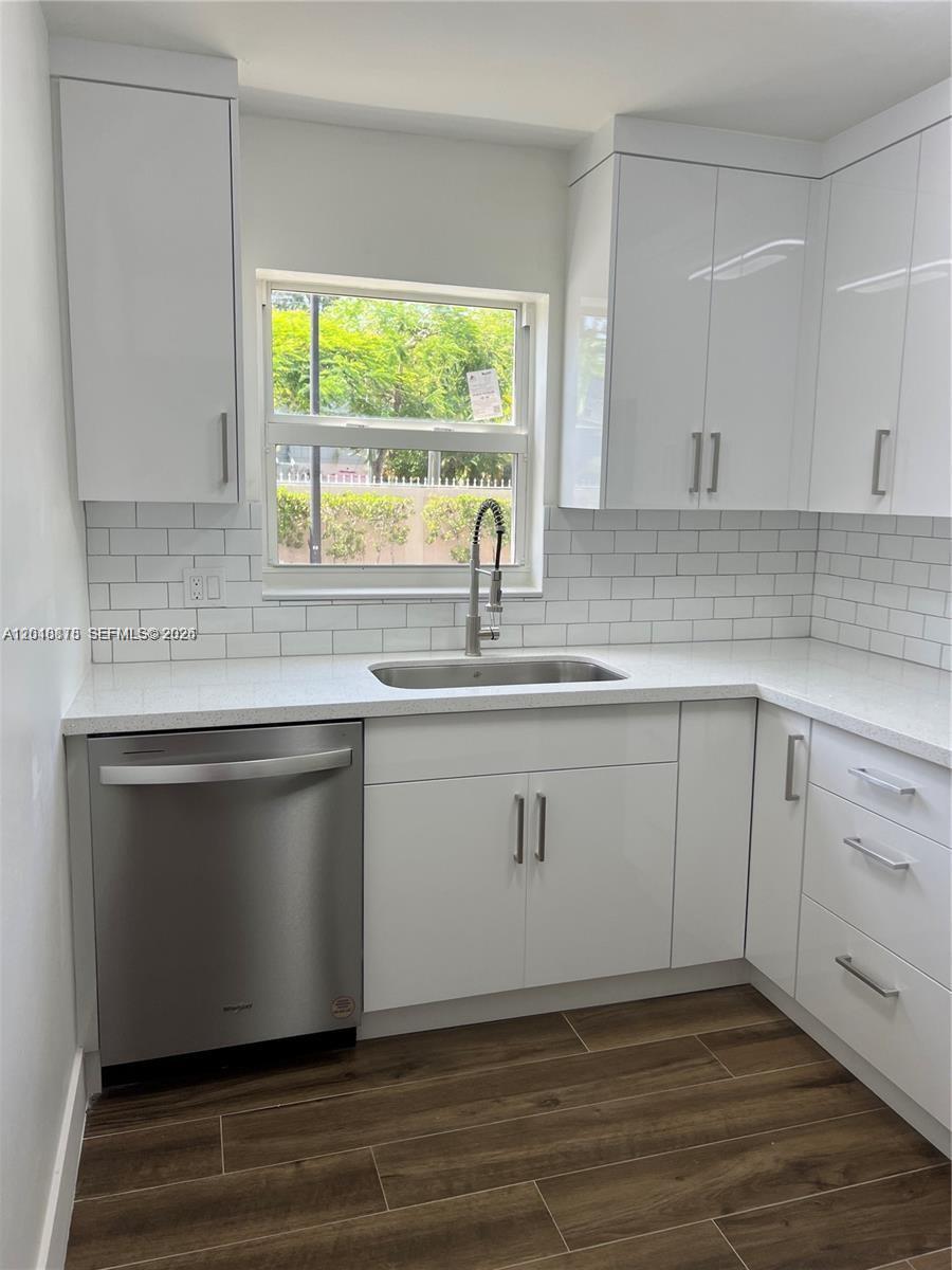 A kitchen features white cabinets, a stainless steel dishwasher, a sink, and subway tile backsplash — 7775 SW 86th St # 105, Miami FL 33143, MIAMI, FL