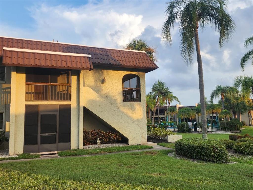 A two-story tan stucco building with a brown tiled roof and screened-in balconies — 1003 S BAYSHORE BOULEVARD UNIT 202, SAFETY HARBOR, FL