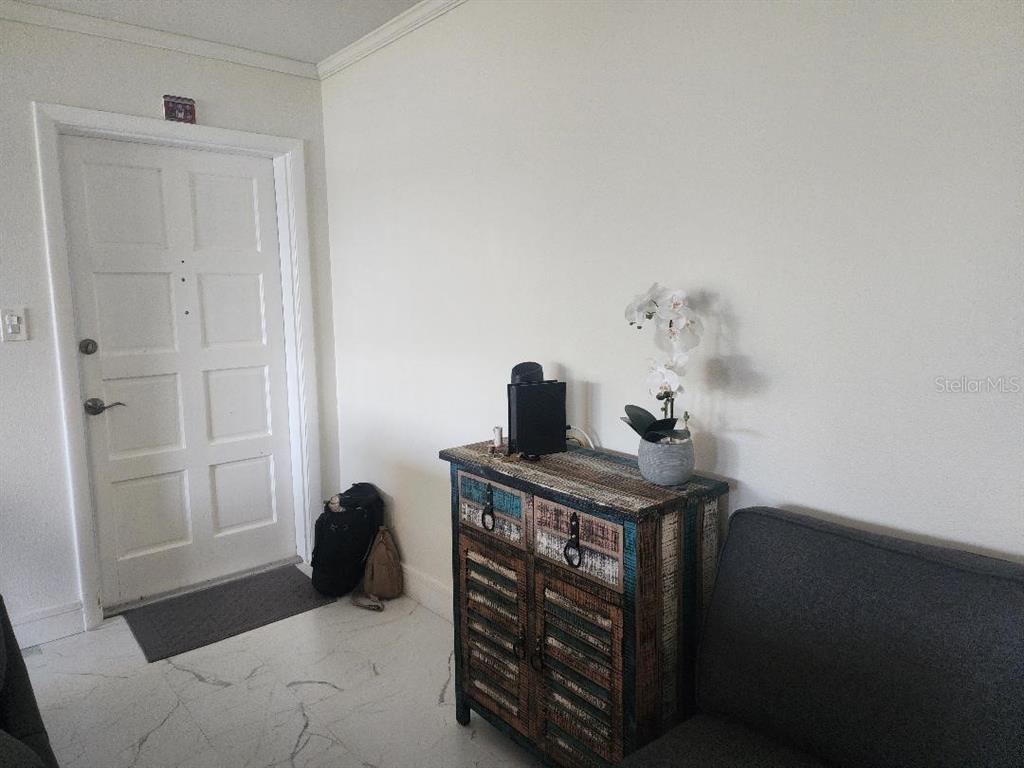 An entryway features a white door, marble-look flooring, and a rustic wooden cabinet — 1003 S BAYSHORE BOULEVARD UNIT 202, SAFETY HARBOR, FL