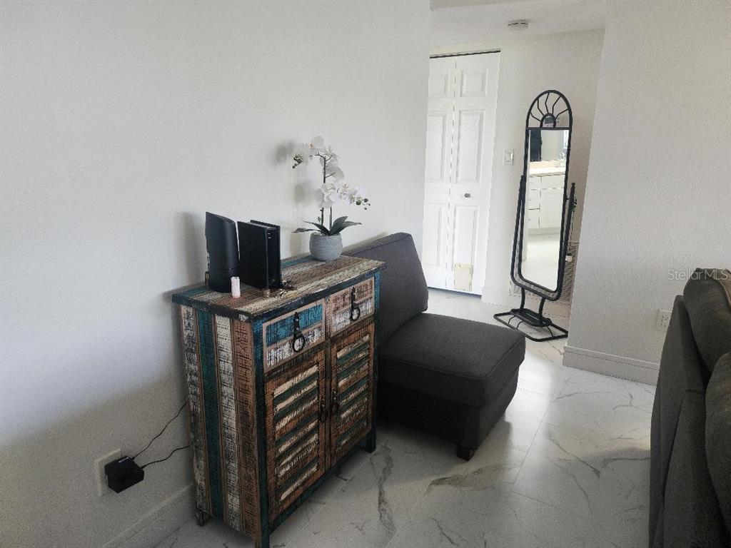 A room features a rustic wooden cabinet, a gray chair, and a standing floor mirror — 1003 S BAYSHORE BOULEVARD UNIT 202, SAFETY HARBOR, FL
