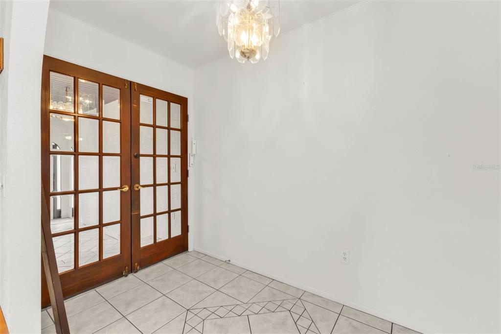 An entryway features white walls, a tiled floor, and a set of wooden French doors — 238 FRY TERRACE SE, PORT CHARLOTTE, FL