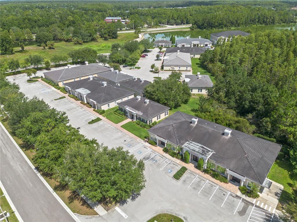 An aerial view shows several commercial office buildings surrounded by parking lots and wooded areas — 5381 PRIMROSE LAKE CIRCLE, TAMPA, FL