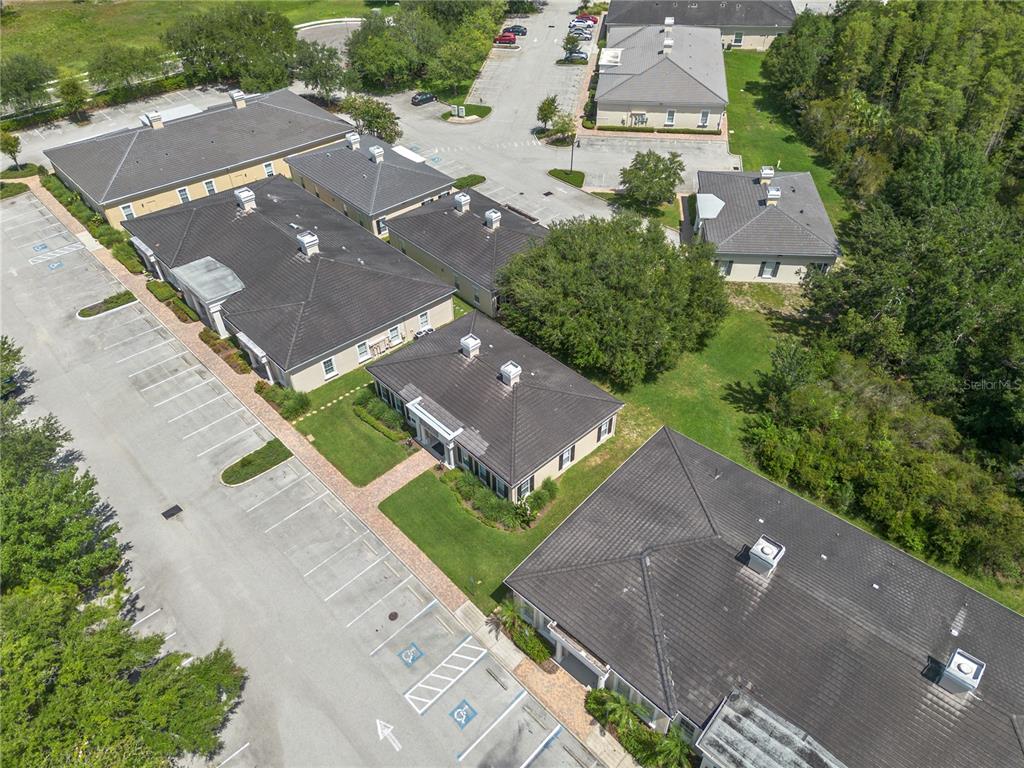 An aerial view shows several commercial buildings with dark roofs surrounded by parking lots — 5381 PRIMROSE LAKE CIRCLE, TAMPA, FL