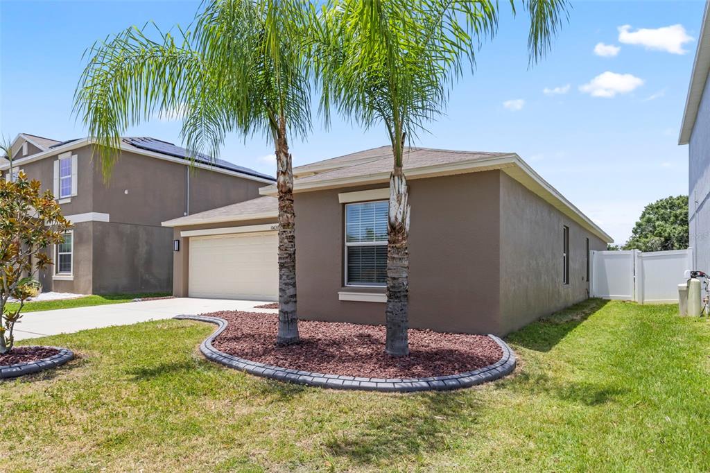 A single-story house with a tan stucco exterior, a two-car garage, and two palm trees — 10633 STANDING STONE DRIVE, WIMAUMA, FL