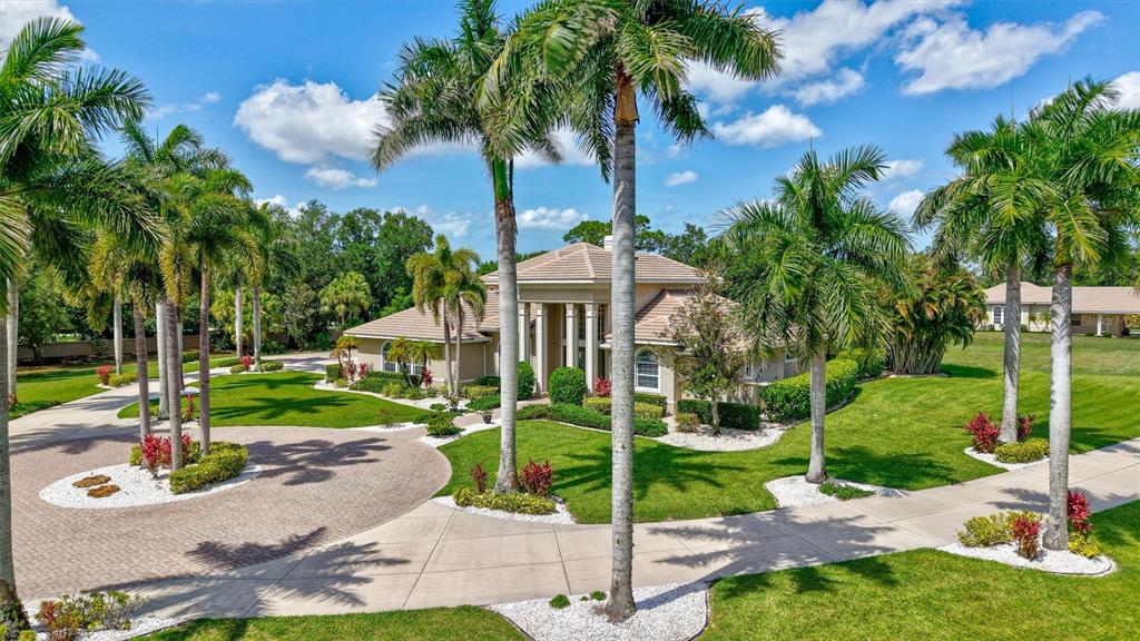 A large two-story house with a tiled roof is surrounded by palm trees and lawns — 1045 FOX CREEK DRIVE, SARASOTA, FL