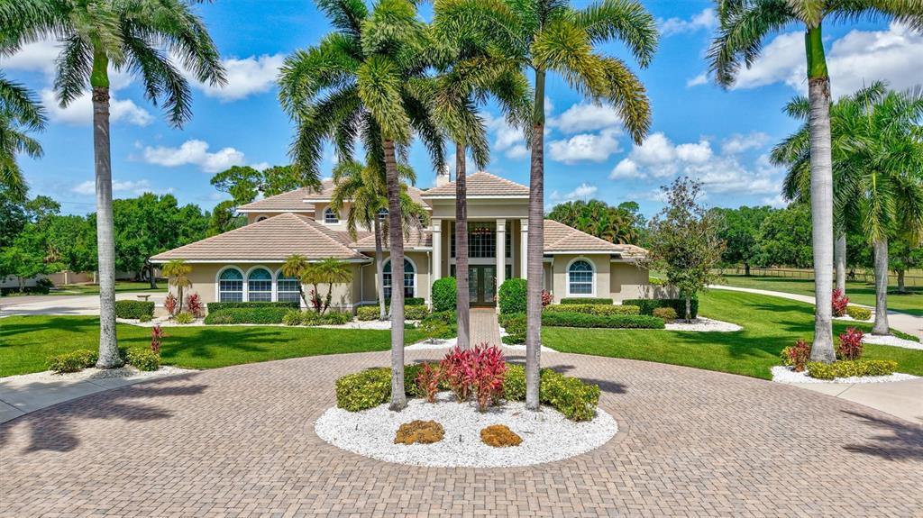 A large two-story house with a paved circular driveway and palm trees in the front yard — 1045 FOX CREEK DRIVE, SARASOTA, FL