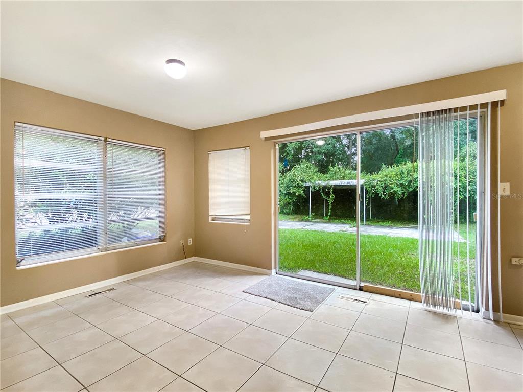 A room with tan walls, tile flooring, large windows, and a sliding glass door to outside — 1119 SW 11TH AVENUE, GAINESVILLE, FL