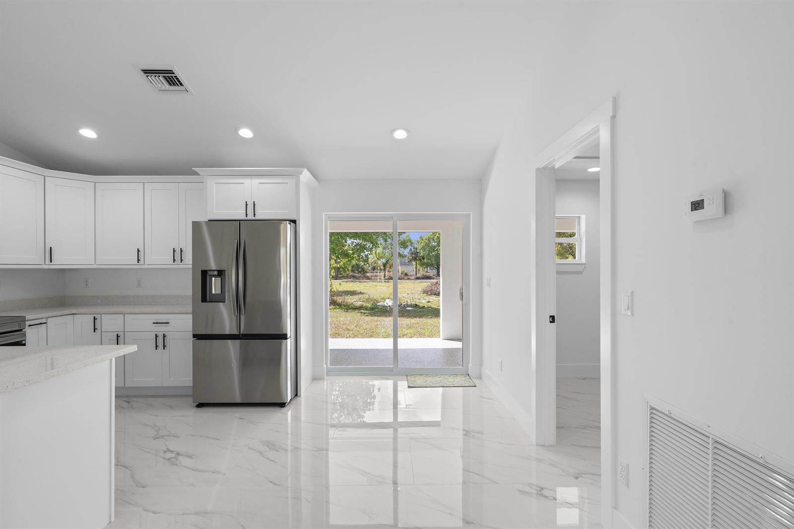 A white house with a dark roof and gravel driveway sits on a grassy lot — 17932 NW 288th Street, Okeechobee FL 34972, OKEECHOBEE, FL