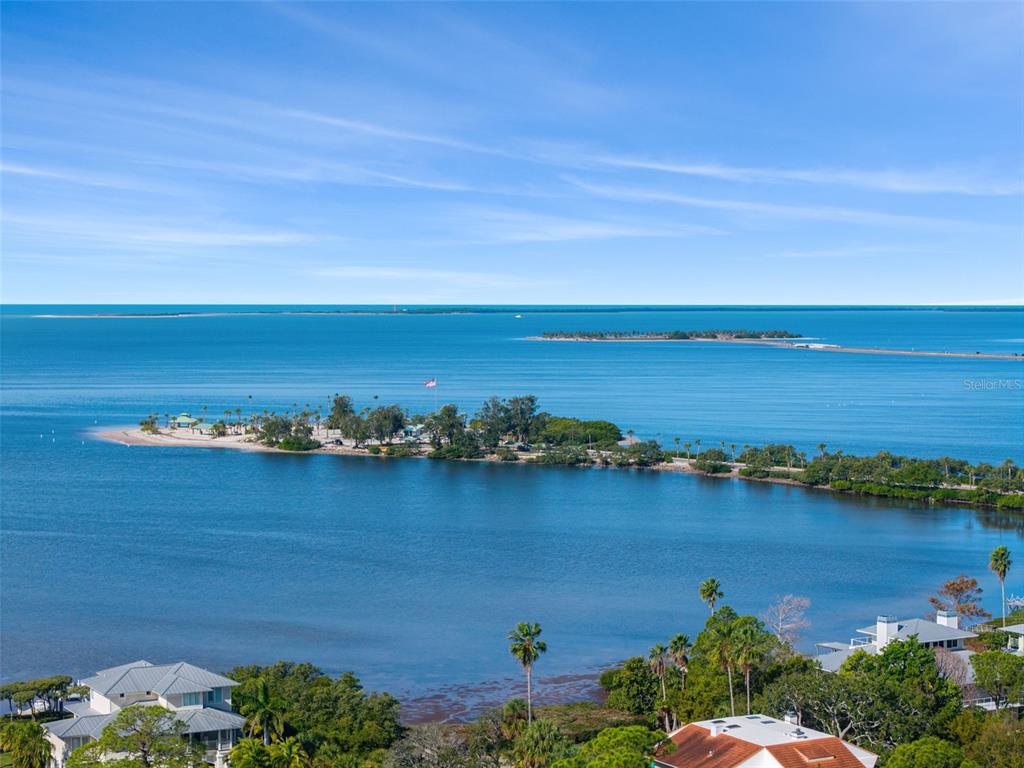 An aerial view shows a vacant, tree-covered lot outlined in blue near a coastal waterfront — VENTNOR AVENUE, TARPON SPRINGS, FL