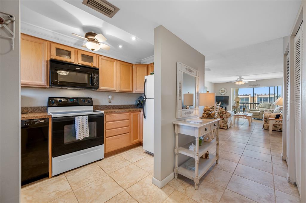 A kitchen with light wood cabinets and black appliances opens into a tiled living area — 1243 S MARTIN LUTHER KING JR AVENUE UNIT C505, CLEARWATER, FL