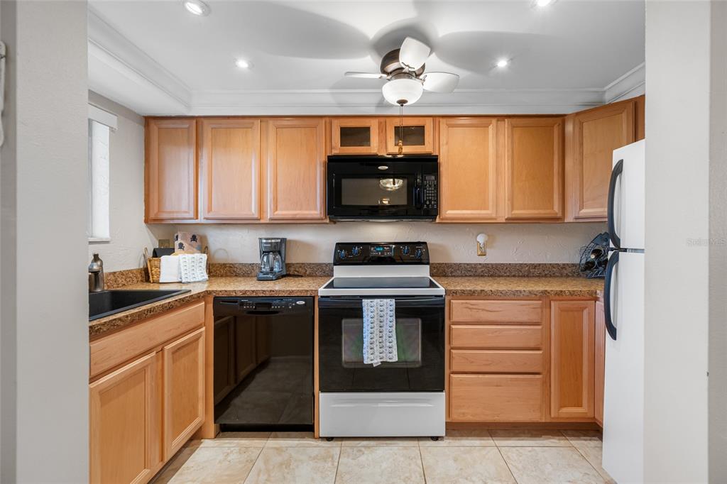 A kitchen features light wood cabinets, granite countertops, a black stove, and a white refrigerator — 1243 S MARTIN LUTHER KING JR AVENUE UNIT C505, CLEARWATER, FL
