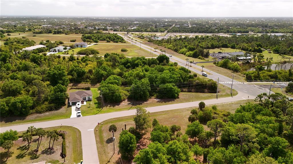 An aerial view shows a residential house, surrounding wooded lots, and a nearby road intersection — 101 ANTILLA DRIVE, ROTONDA WEST, FL