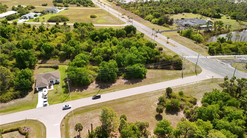 An aerial view shows a house, a wooded lot, and intersecting roads in a suburban area — 101 ANTILLA DRIVE, ROTONDA WEST, FL