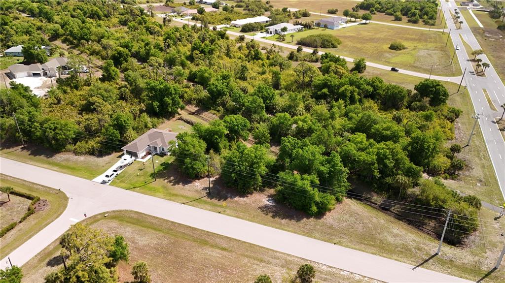 An aerial view shows a single-family home surrounded by dense trees and nearby roads — 101 ANTILLA DRIVE, ROTONDA WEST, FL
