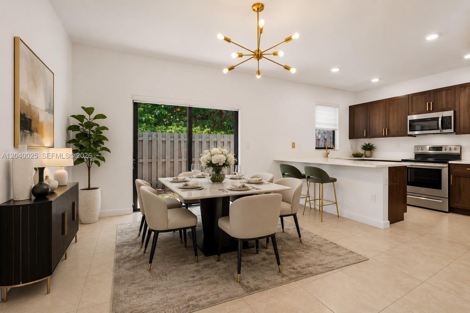 A dining area with a modern chandelier and table sits adjacent to a kitchen — 670 NE 207th St, Miami FL 33179, MIAMI, FL