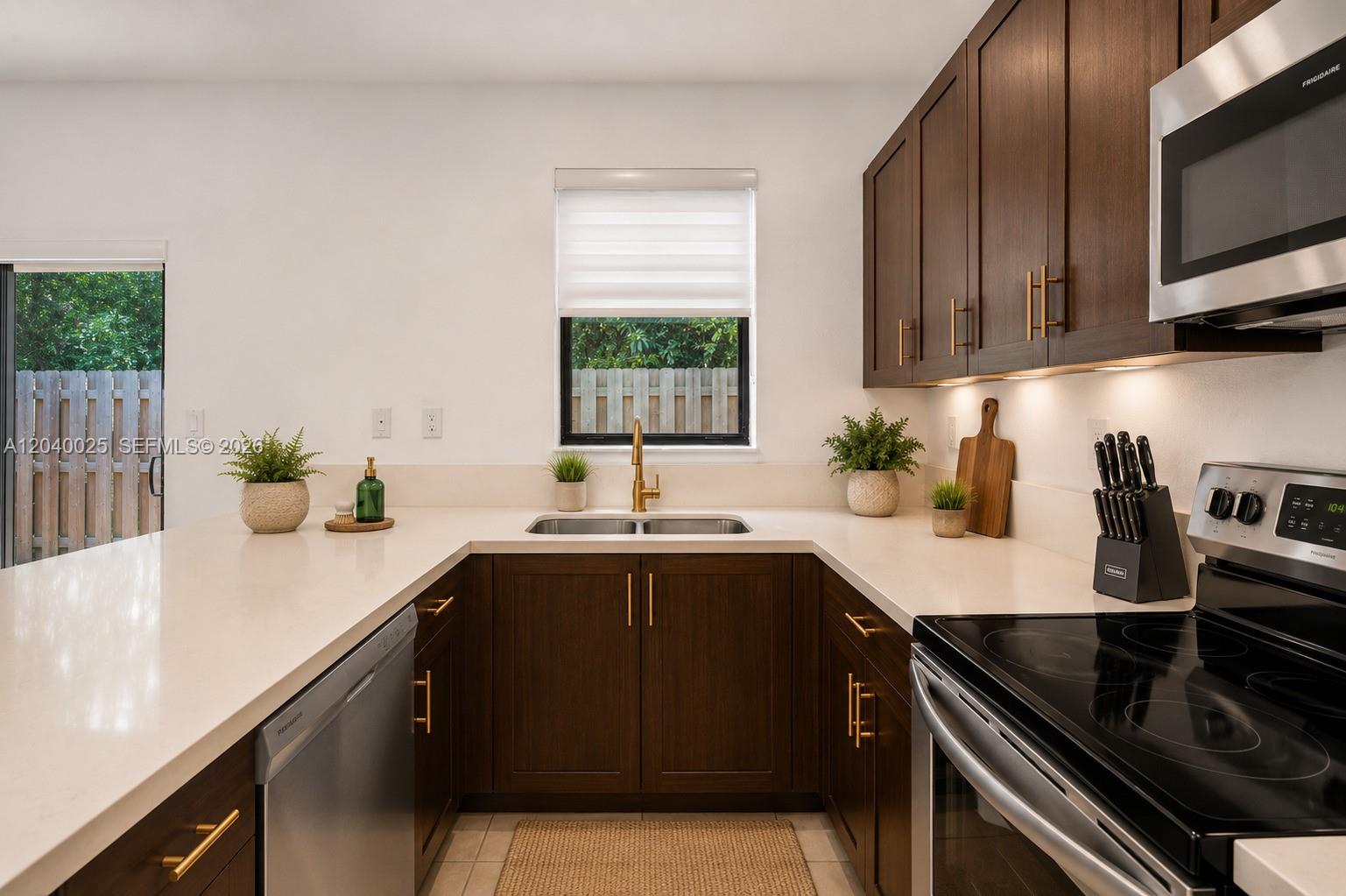 A kitchen features dark wood cabinets, white countertops, stainless steel appliances, and a window view — 670 NE 207th St, Miami FL 33179, MIAMI, FL