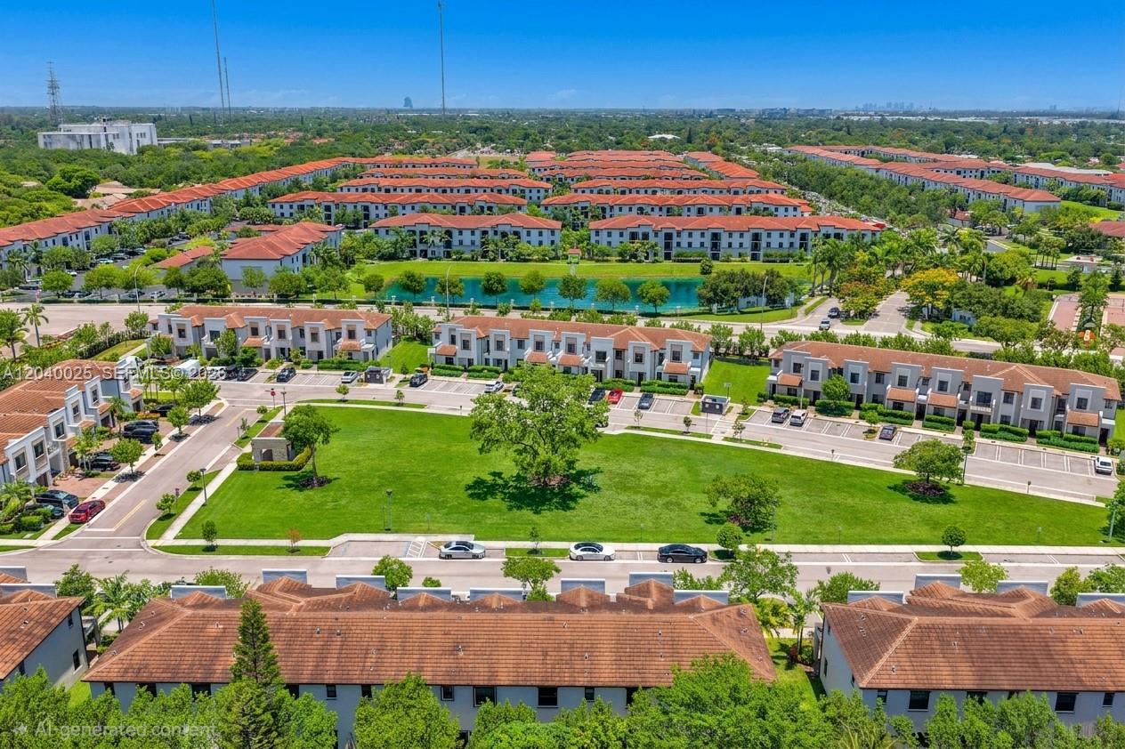 An aerial view shows multiple rows of townhouses surrounding a large green lawn and pond — 670 NE 207th St, Miami FL 33179, MIAMI, FL