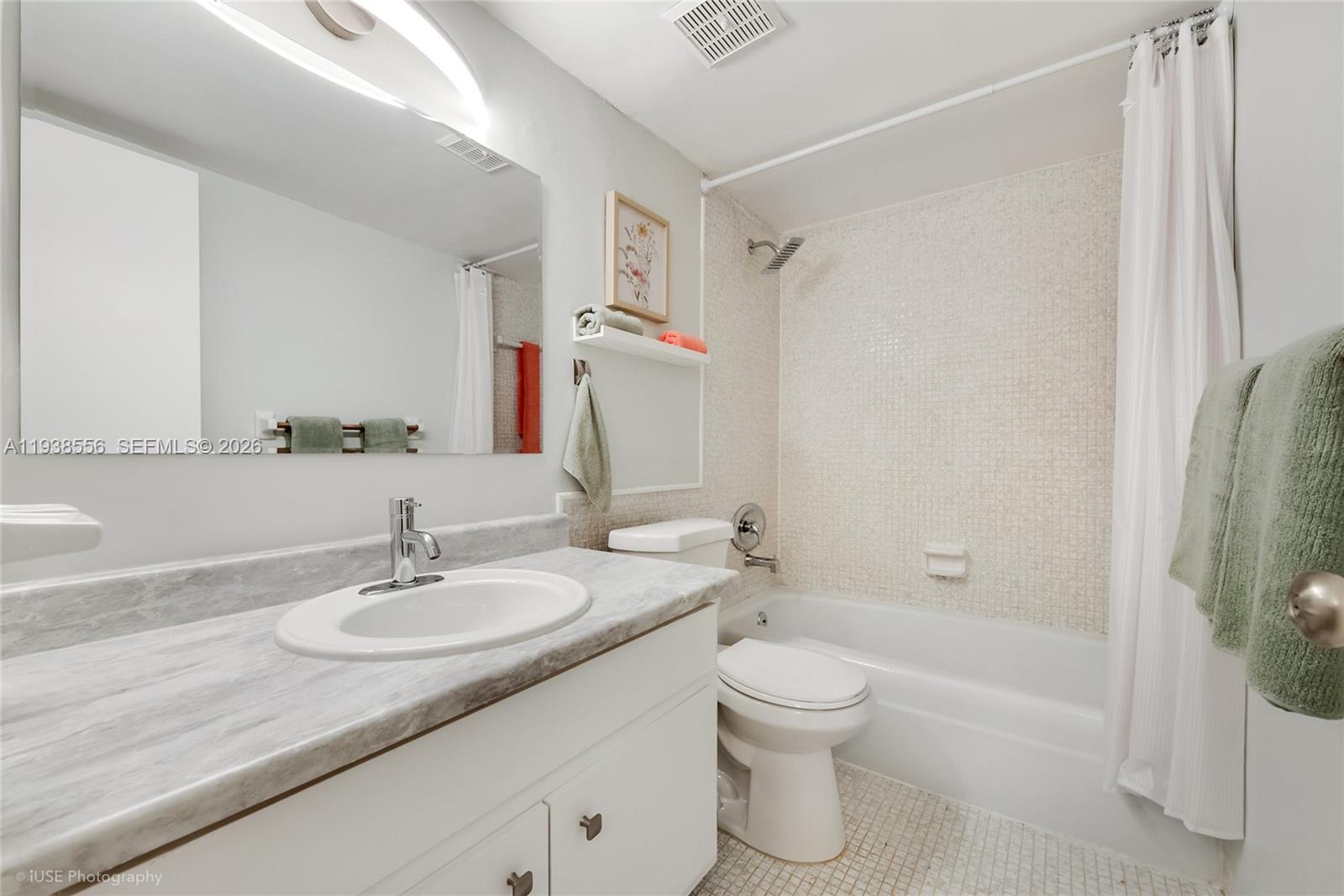 A bathroom features a white vanity with a marble countertop, a toilet, and a tiled shower — 7403 SW 82nd St # 210N, Miami FL 33143, MIAMI, FL