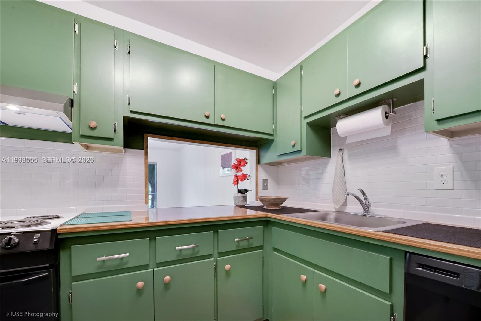A kitchen features green cabinets, a wood countertop, and a white subway tile backsplash — 7403 SW 82nd St # 210N, Miami FL 33143, MIAMI, FL