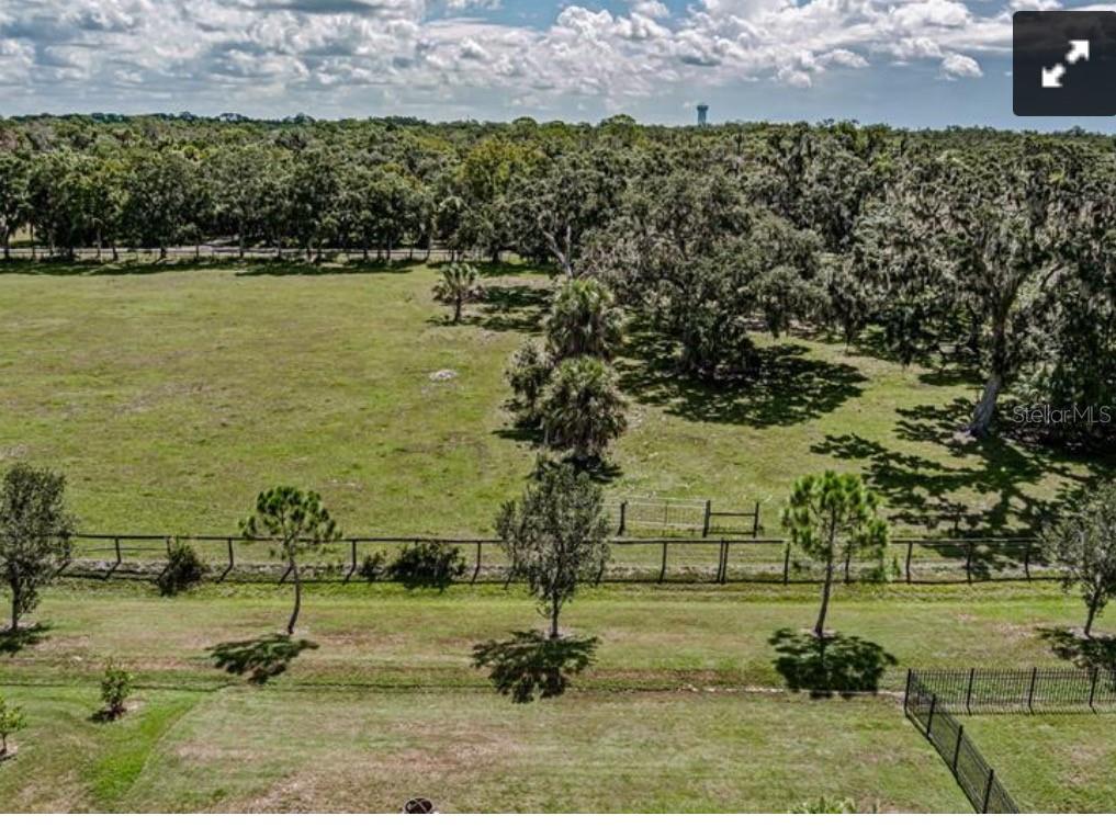 An aerial view shows a large, grassy pasture bordered by trees and a wire fence — 7114 58TH TERRACE E, PALMETTO, FL