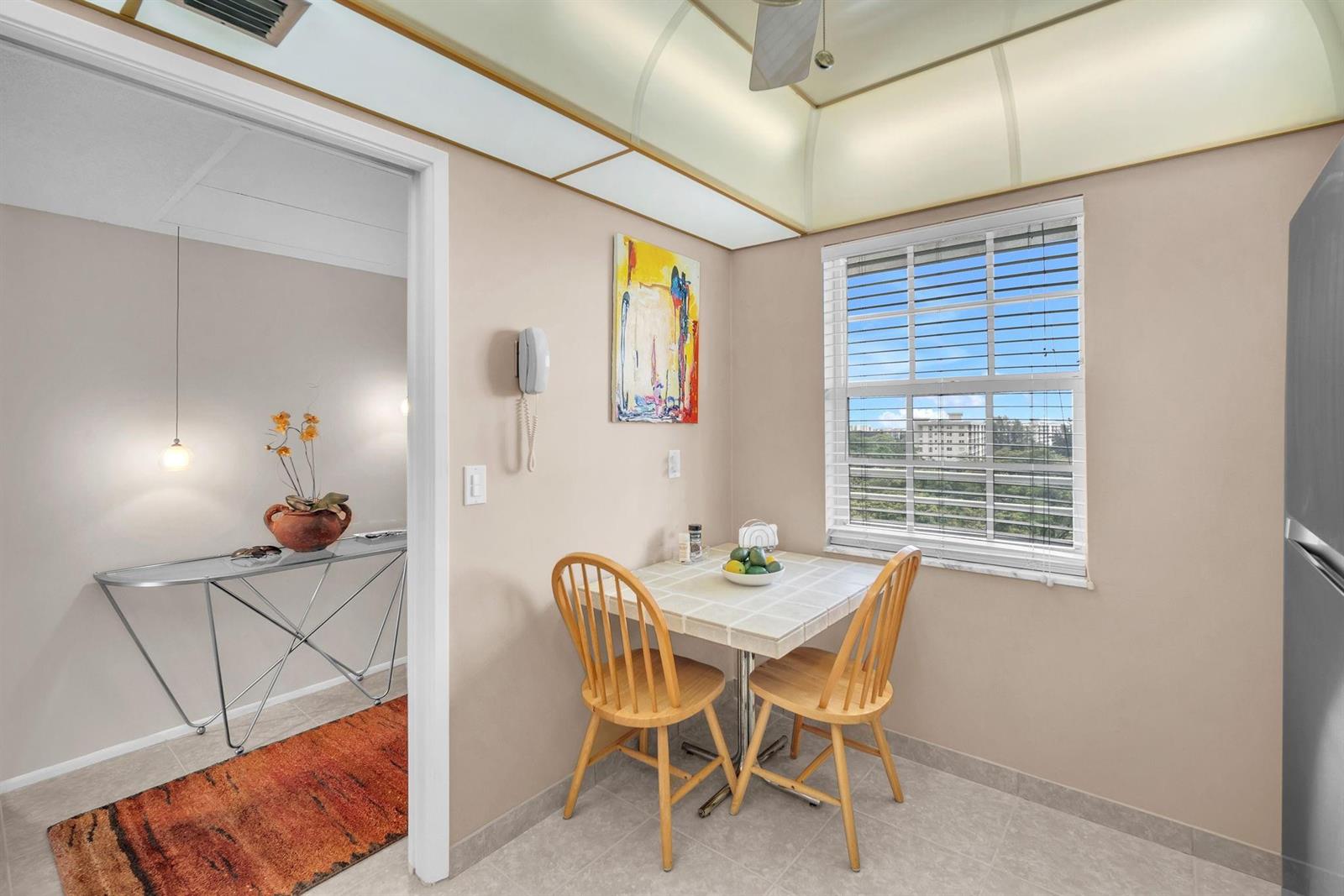 A small dining area features a tiled table, two wooden chairs, and a window view — 605 Oaks Drive # 907, Pompano Beach FL 33069, POMPANO BEACH, FL