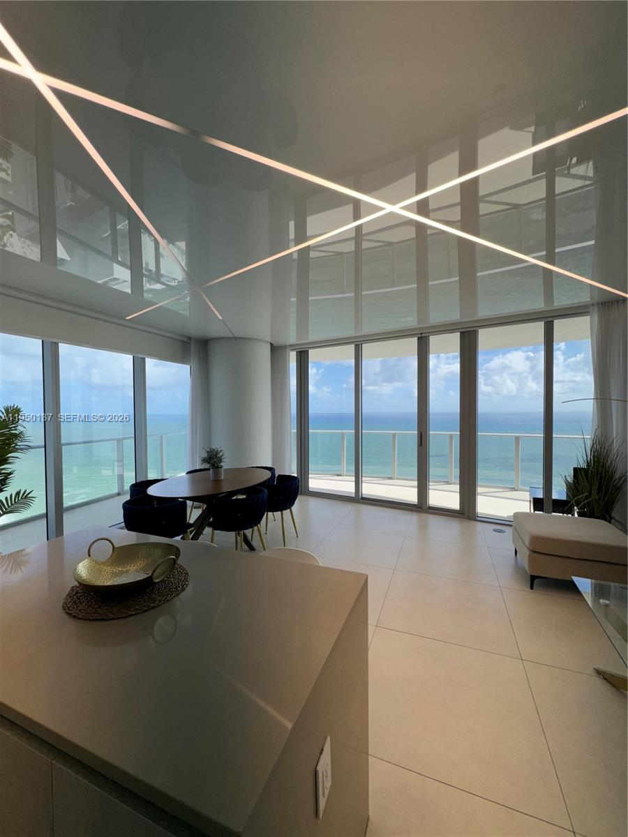 A modern dining area features a glossy ceiling with integrated lighting and floor-to-ceiling ocean views — 4111 S Ocean Dr # 3002, Hollywood FL 33019, HOLLYWOOD, FL