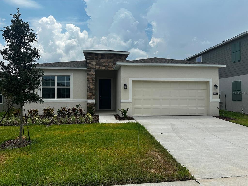A single-story house features a stone-accented entryway, a two-car garage, and a front lawn — 3216 ALPINE WAY, DAVENPORT, FL