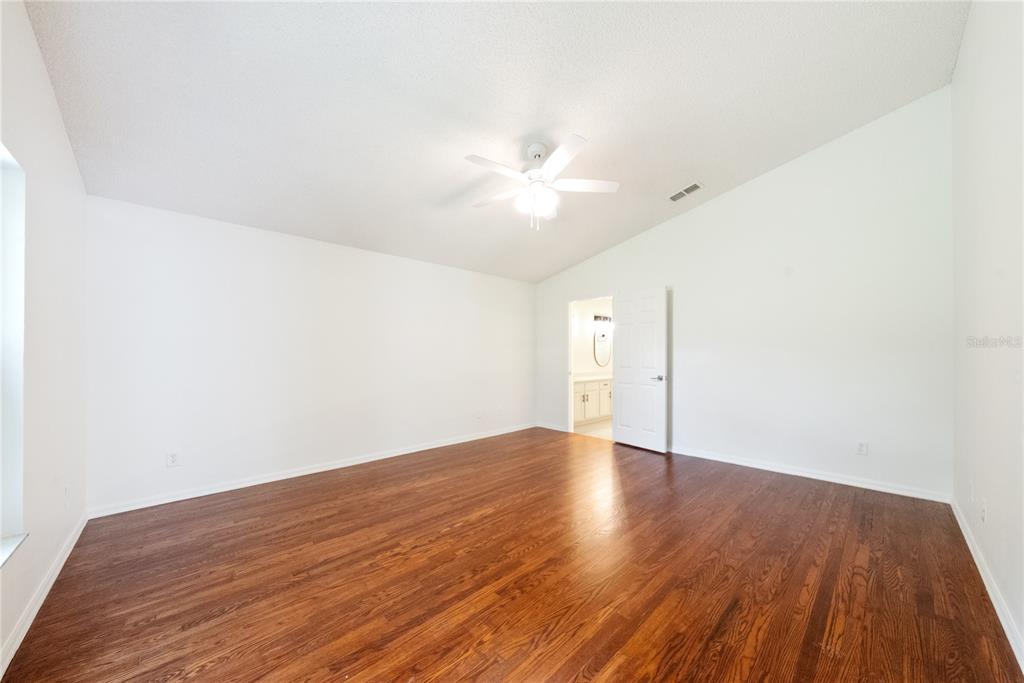 A bright kitchen features white cabinets, light countertops, white appliances, and tiled flooring — 9064 SW 91ST CIRCLE, OCALA, FL
