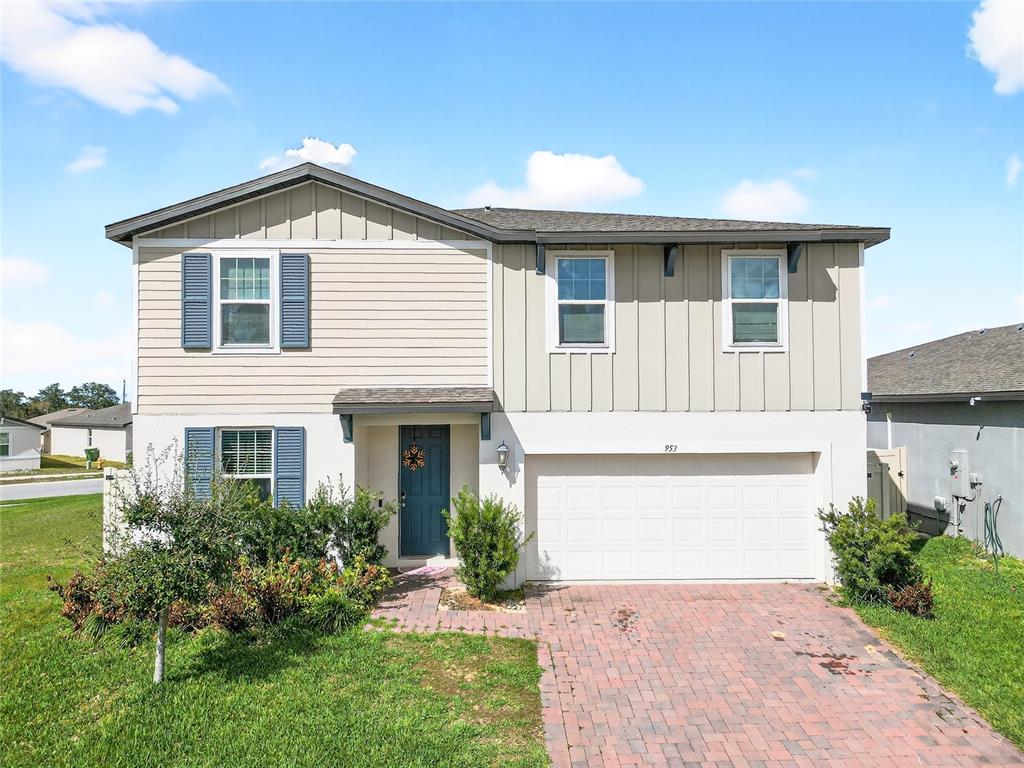 A two-story house features a mix of horizontal and vertical siding, blue shutters, and a garage — 953 CAMBRIDGE DRIVE, WINTER HAVEN, FL