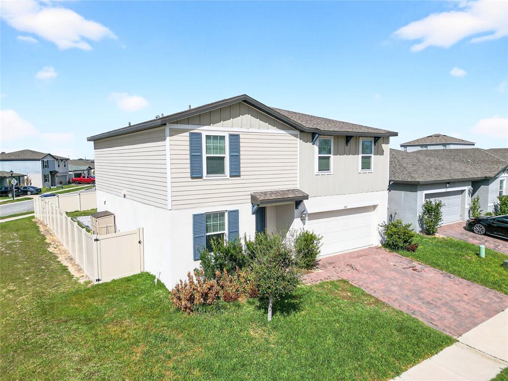 A two-story house with beige siding, blue shutters, and a brick driveway — 953 CAMBRIDGE DRIVE, WINTER HAVEN, FL