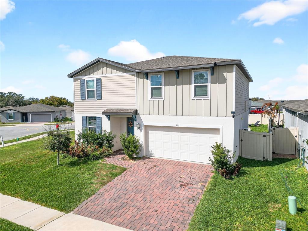 A two-story house with a brick driveway, white garage door, and light-colored siding — 953 CAMBRIDGE DRIVE, WINTER HAVEN, FL