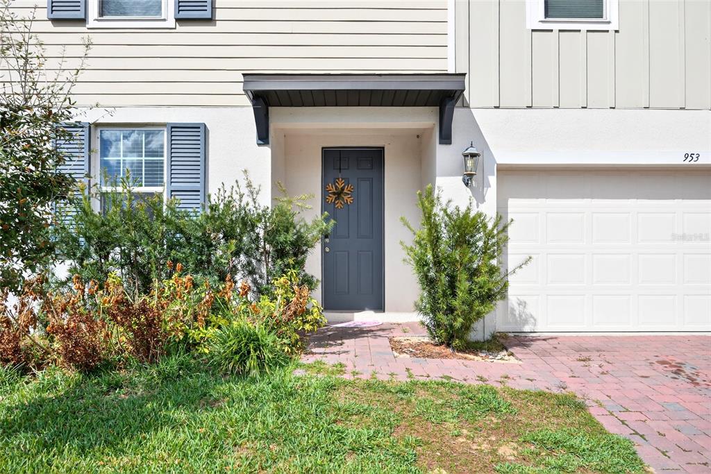 The exterior of a house features a gray front door, a garage, and landscaping — 953 CAMBRIDGE DRIVE, WINTER HAVEN, FL