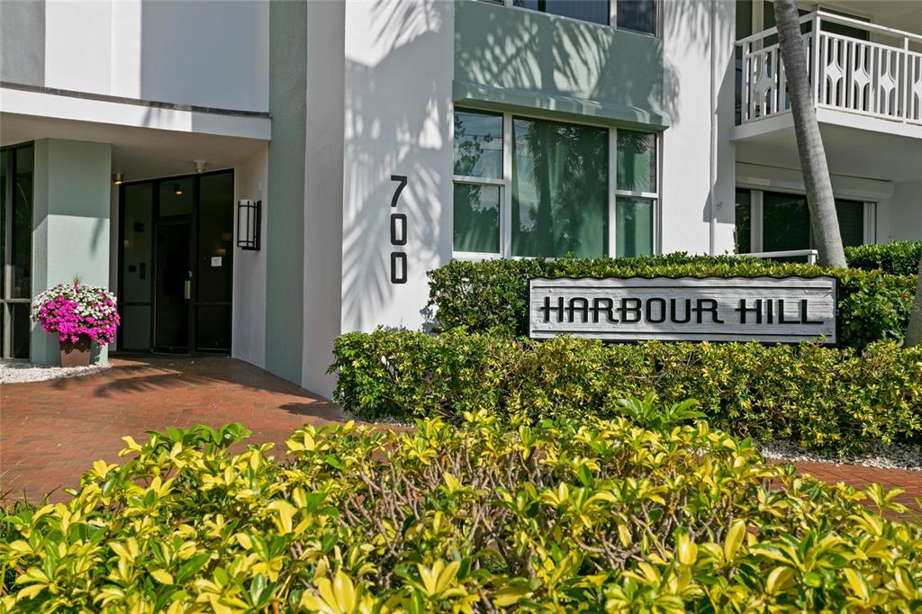 A multi-story white apartment building with balconies and palm trees stands near a street corner — 700 BEACH DRIVE NE UNIT 603, ST PETERSBURG, FL