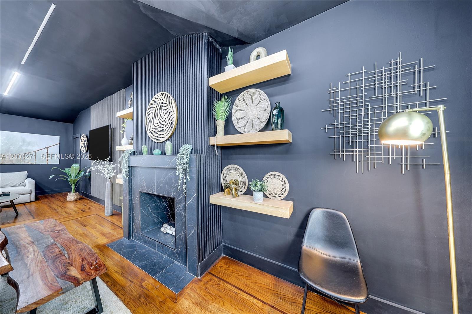 A living room features a black marble fireplace, slatted wall accents, and floating wooden shelves — 2612 SW 12th St, Miami FL 33135, MIAMI, FL