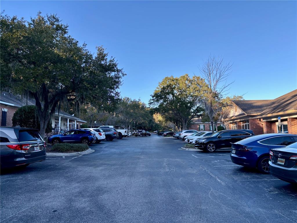 A paved parking lot is situated between two single-story brick buildings lined with trees — 230 NW 76TH DRIVE UNIT B, GAINESVILLE, FL
