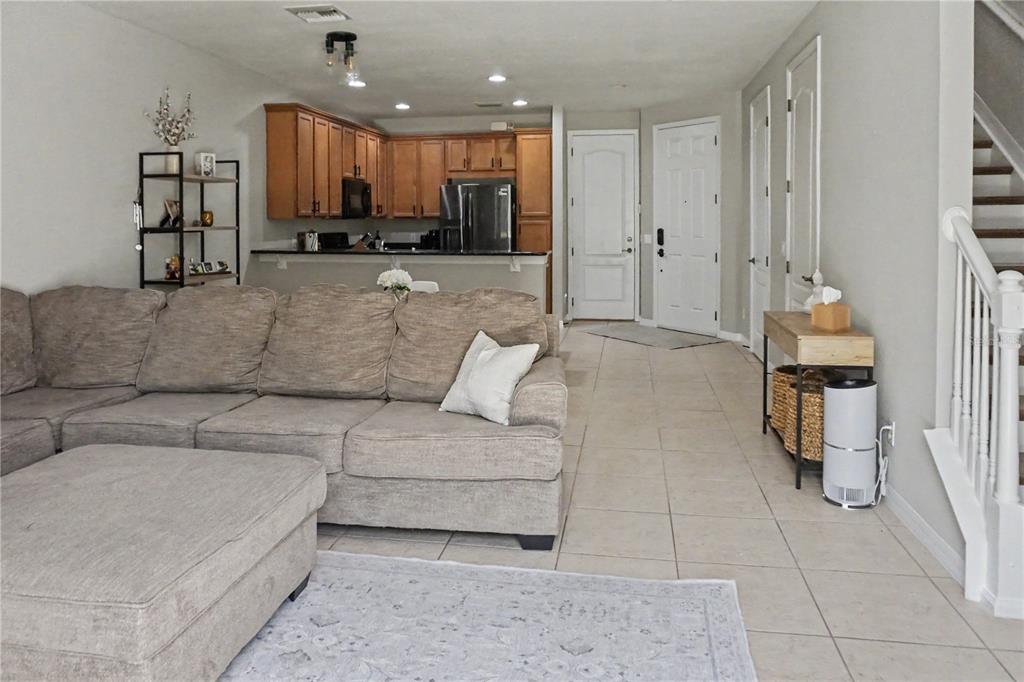 A living room with a sectional sofa, tile floors, and an open kitchen with wood cabinets — 1828 GARDEN SAGE DRIVE, OVIEDO, FL