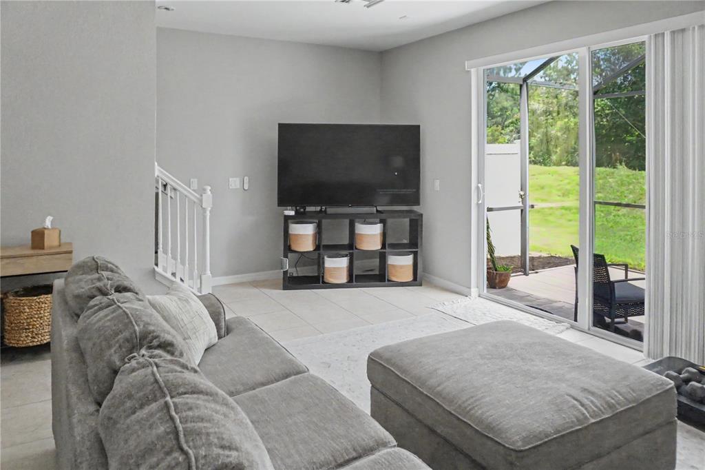 A living room features a gray sofa, a television on a storage unit, and sliding doors — 1828 GARDEN SAGE DRIVE, OVIEDO, FL