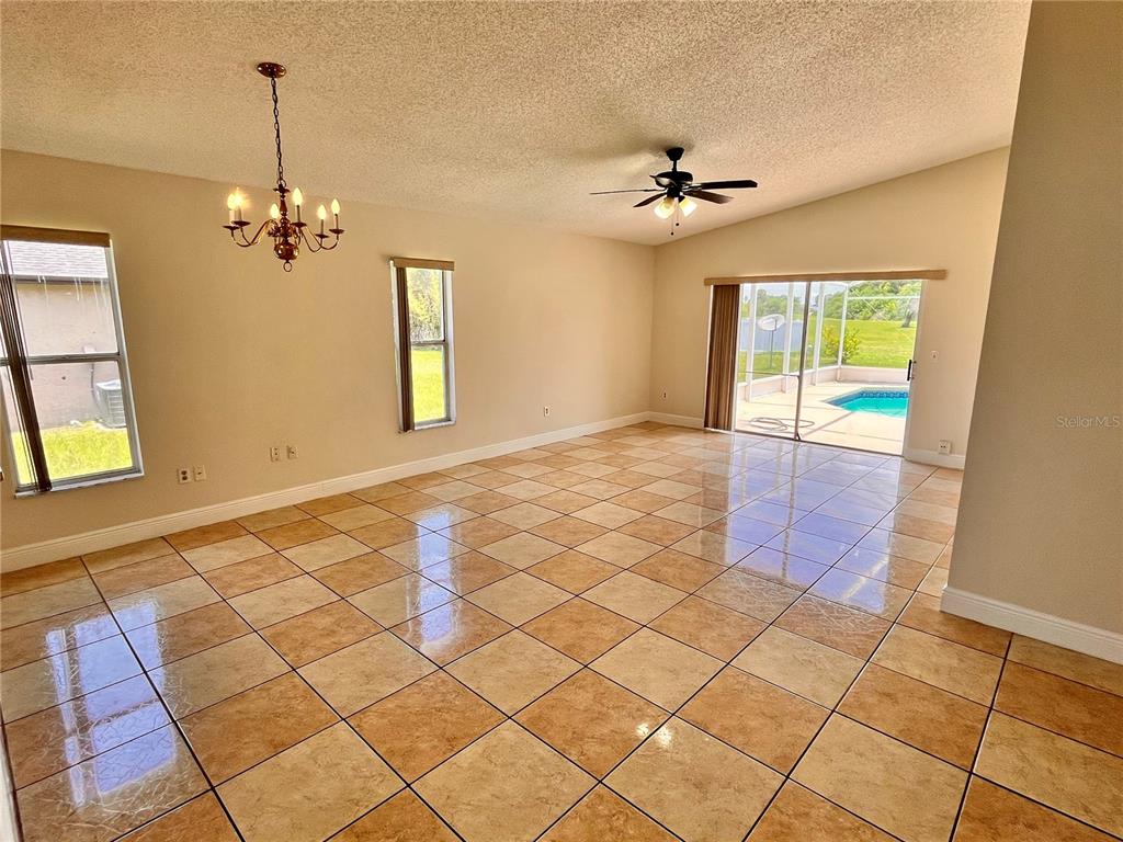 A spacious living room features tan tile flooring, a ceiling fan, and sliding glass doors — 13534 TEXAS WOODS CIRCLE, ORLANDO, FL