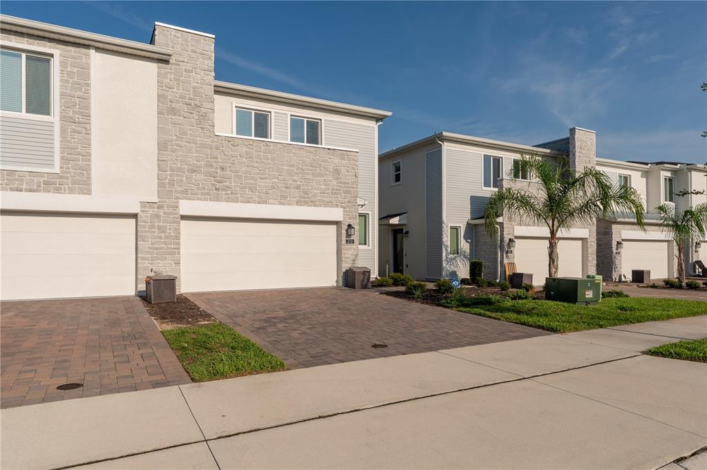 A view of the exterior of two modern townhomes with stone facades and paved driveways — 210 BOGEY DRIVE, DAVENPORT, FL