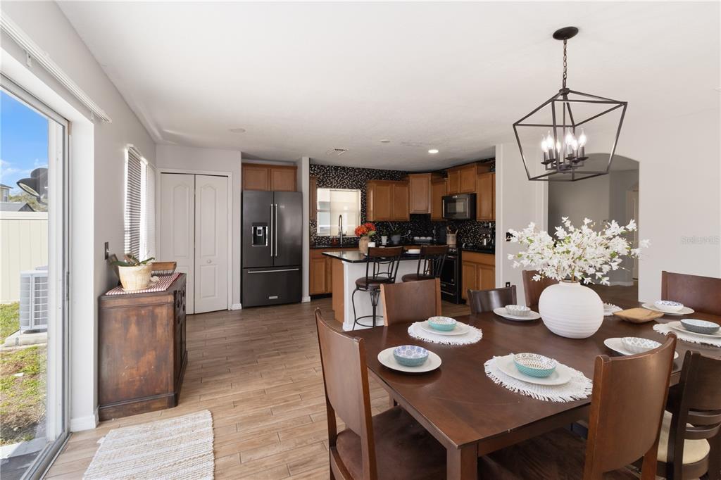 A dining area with a wooden table and chairs sits adjacent to a kitchen with cabinets — 7327 LUMBER PORT DRIVE, RUSKIN, FL