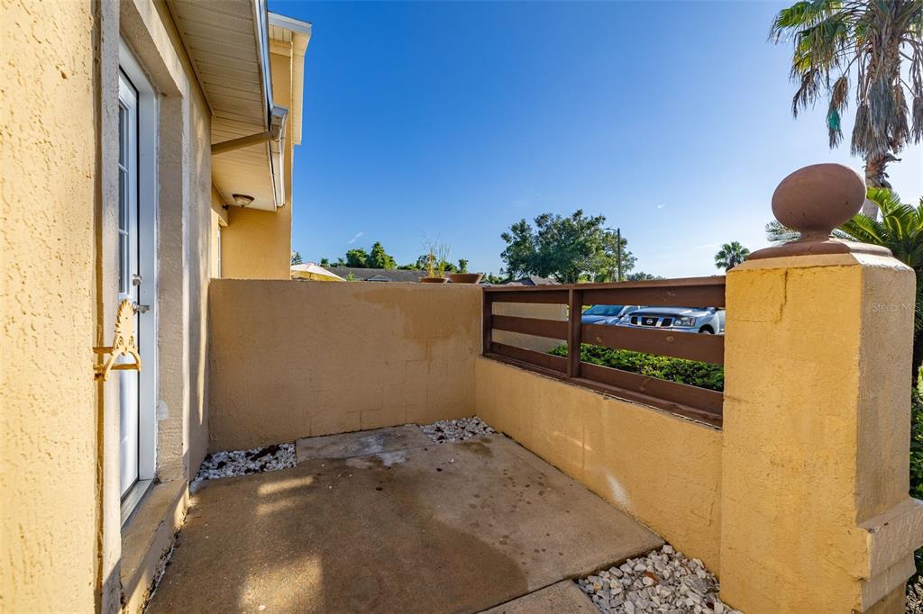 A small concrete patio features a low stucco wall and a wooden privacy fence — 3128 SANDY SHORE LANE, KISSIMMEE, FL