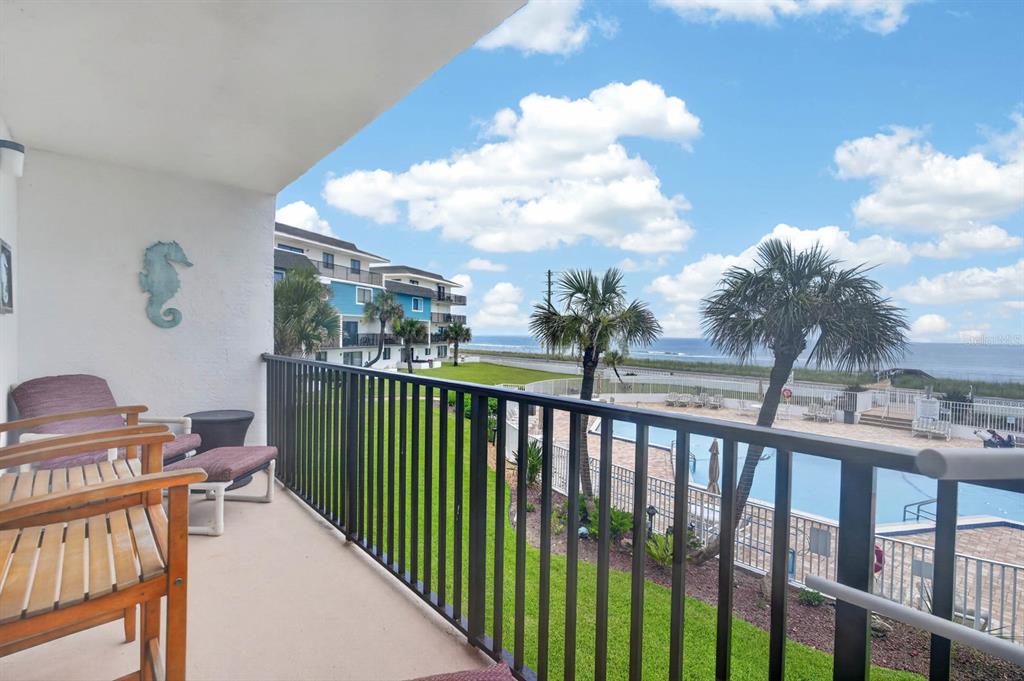 A balcony overlooks a swimming pool, green lawn, and the ocean in the distance — 3500 S OCEAN SHORE BOULEVARD UNIT 211, FLAGLER BEACH, FL