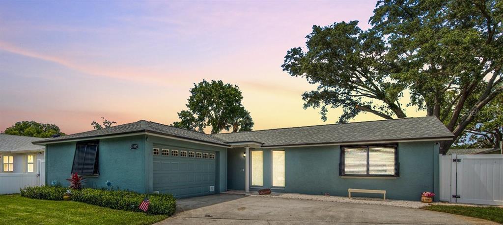 A teal single-story house with a two-car garage, white trim, and a large oak tree — 11987 106TH AVENUE, SEMINOLE, FL