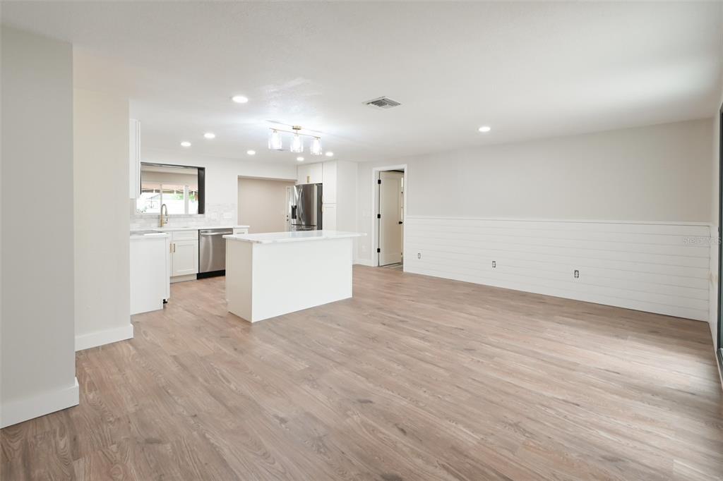 A bright, open-concept kitchen and living area featuring white cabinetry, a marble-topped island, and shiplap — 11987 106TH AVENUE, SEMINOLE, FL