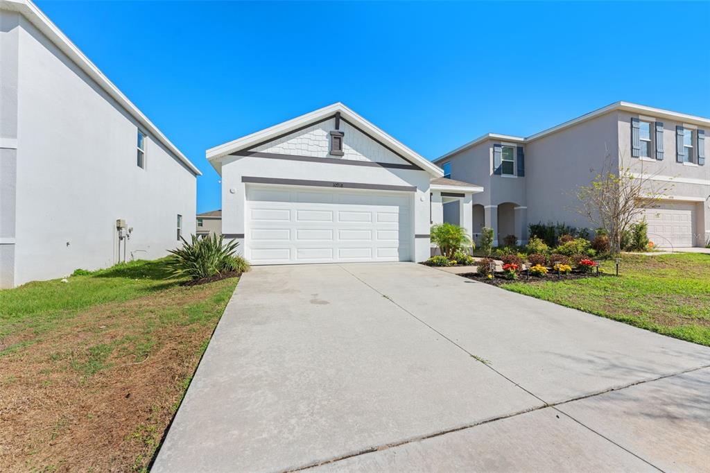 A single-story house with a white garage and a concrete driveway under a clear sky — 10918 TRAILING VINE DRIVE, TAMPA, FL
